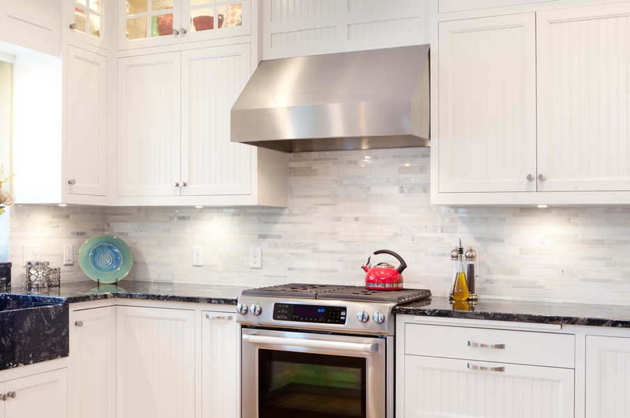 Kitchen with white and gray backsplash and white cabients